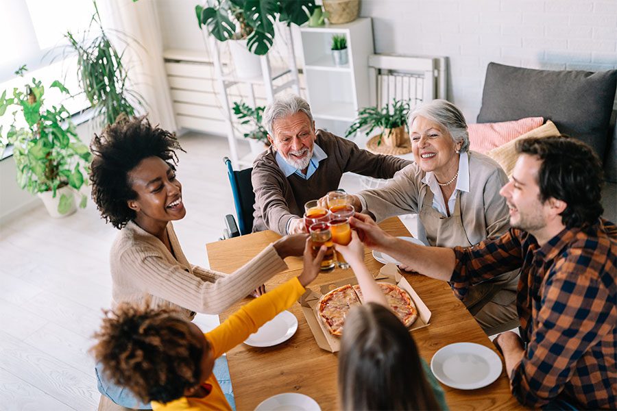 Insurance Quote - View of Cheerful Families Sitting Around the Table Making a Toast Before Eating Pizza Together