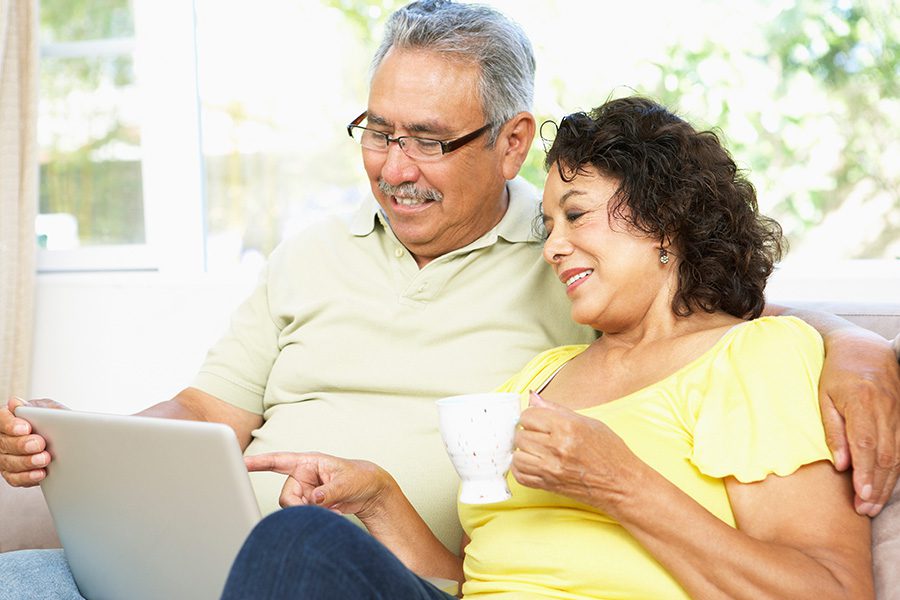 Blog - Older Couple Sitting Together in Their Home While They Smile and Look at the Laptop